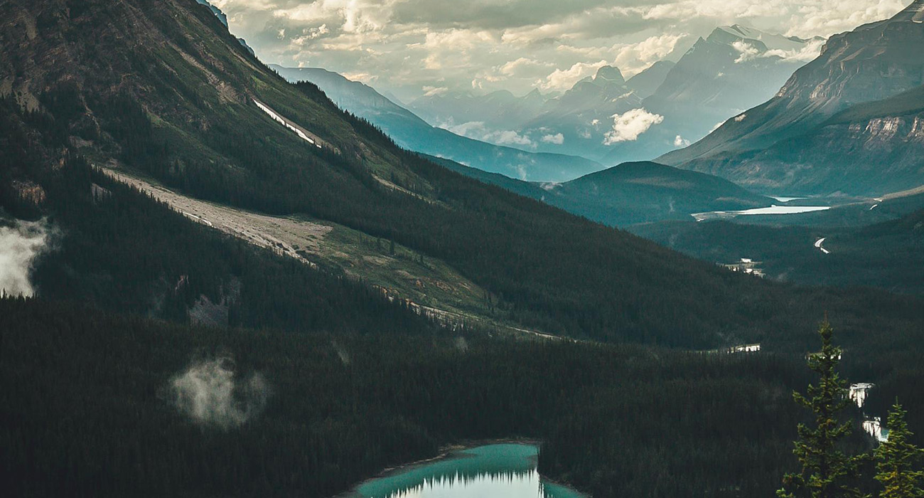 Alpine vista with tall treelined mountains and an alpine lake